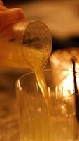 A cocktail is poured into a glass with ice under warm, dim lighting, creating a cozy atmosphere video