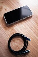 Charging smartphone with usb cable wooden surface close-up view in modern home environment photo