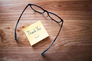 Grateful gesture thank you note with glasses wooden desk personal touch cozy home office close-up view photo