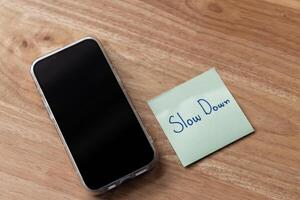 Mindfulness reminder slow down message next to smartphone wooden table photo