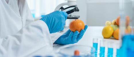 Scientist examining orange with magnifying glass photo
