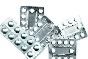 Pack of pills to improve health. Tablets and capsules in an aluminum container on a white table. photo