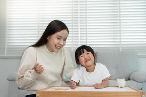 Mother day, Happy Asia mother play and learn drawing for little girl. Funny family is happy and excited in the house. Mother and daughter having fun spending time together. Holiday, Activity. photo