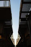 Converging lines of pedestrian bridge creating symmetrical composition against clear sky during sunset, with metal grid flooring and railings, offering unique perspective on urban infrastructure photo