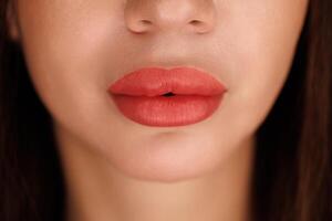 Closeup of symmetrical, full lips after enhancement with pink pigment and smooth finish. photo