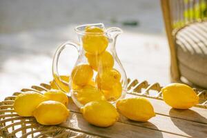 Fresh lemons in a glass pitcher photo
