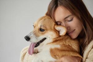 Girl hugging Corgi puppy with closed eyes, emotional moment of love and affection, close-up portrait. photo