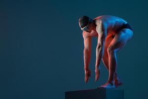 Swimmer ready to dive from block, intense side lighting, athletic pose in studio setting. photo