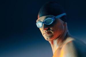Determined swimmer wearing goggles and cap, highlighted by blue and orange studio lighting. photo