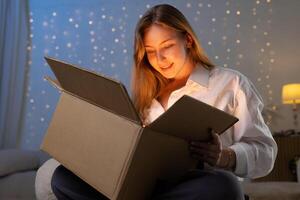 Smiling Woman Opens Glowing Package at Home Representing Unboxing Gift Delivery and Holiday Shopping photo