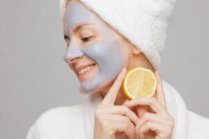 Smiling Woman with Clay Facial Mask and Lemon, Firming and Moisturizing Anti Aging Spa Skin Care Concept photo