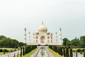 Taj Mahal reflecting in the water channel with tourists walking in Agra, India photo