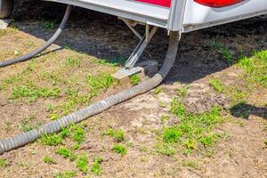 On the bottom of the camper, a connection between hoses and support structures on the ground. sewerage system photo