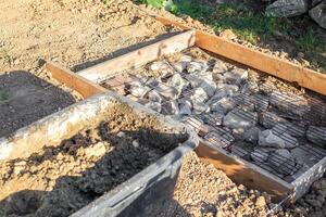 black tub filled with a mixture of sand and water sits next to a construction site prepared with rocks and wire mesh for pouring concrete photo