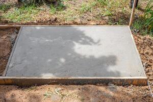 Freshly poured concrete slab, smooth and level surface, framed with wood, stands on the ground. Foundation construction. photo