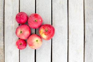 A bunch of bright juicy red apples lie neatly on a weathered wooden surface,top view,copy space. Fruit harvest photo