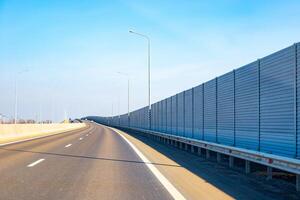 Anti-Noise screen along the road with moving transport. Noise protection fence preventing noise pollution photo