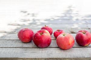 Bunch of red apples artfully arranged on weathered wooden surface with shadows from tree branches. rustic composition with copy space photo