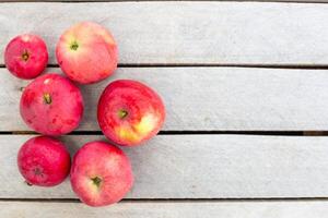 bunch of bright juicy red apples lie neatly on a weathered wooden surface,top view,copy space. Fruit harvest photo