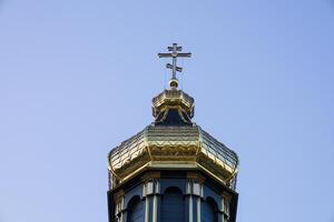 A stunning golden dome adorned with a cross rises above an old church, framed by a bright blue sky during a sunny day photo