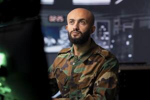 Air defense command professional using radar infrastructure to detect incoming ballistic missiles. Military soldier in base of operations scanning rockets approaching country, deploying shields photo