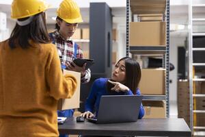 Asian staff members at a fulfillment center printing invoices and prepares packages with bar codes and shipping labels. Small business handles local delivery and in house order processing. photo