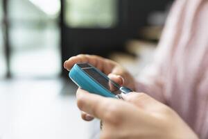 Nurse checking blood sugar levels using glucometer device, routine health check in hospital waiting room. Asian woman receiving support and learning to track glucose levels. Close up. photo