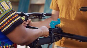 Detailed view showing people utilizing customized repair platform and tools to mend bicycle in backyard. Close-up shot of young diverse couple grabbing and clamping bike for fixing. photo