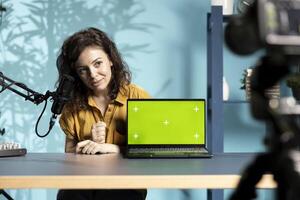 Tech specialist assessing mockup laptop performance, talking about parts used inside, filming with professional camera. Entertainer reviewing green screen notebook on technology internet channel photo