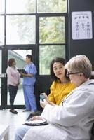 Older physician using a glucometer for blood sugar monitoring, doing a routine checkup for asian patient suffering from diabetes. Measuring glucose and sugar levels. Device training. photo