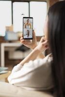 Focused female manager works from home, using cellphone for virtual discussion with team members on startup goals. Businesswoman having strategic planning meeting with colleagues on call. photo