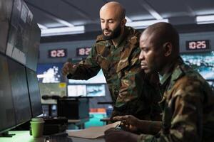 Team of army operatives managing air traffic control for military aircrafts, using radar surveillance. Military agent and colleague following enemy units on reconnaissance satellite system photo