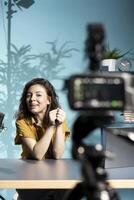 Content creator filming vlog with high tech gear in professional studio, speaking into microphone equipment. Cheerful vlogger talking to subscribers about trending topics on online channel photo