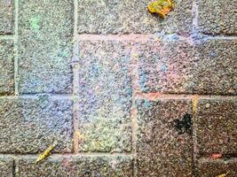 Colorful paint splattered on a brick wall creating an abstract pattern photo