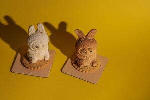 Cute Labubu character-shaped cakes on round biscuits with shadows, studio shot on yellow background photo