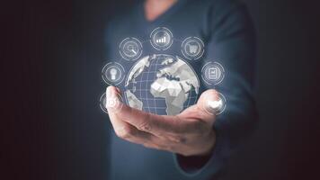 holds globe representing interconnect of the digital world. Icons for search, graphs,shopping carts,light bulbs,and more surround the world, symbol the vast possibilities of technology and business. photo