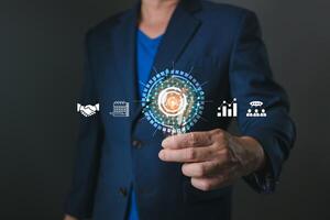 A professional holds a glowing target icon surrounded by symbols of teamwork, planning, and growth, emphasizing goal setting, business strategy, and achieving success through collaboration and focus. photo