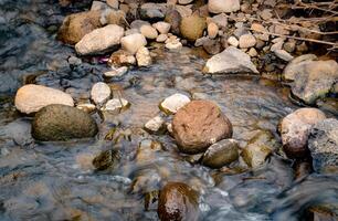 Small stones of various sizes are in the middle of the river flow photo