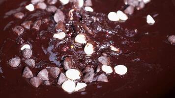 Spoon stirring melted chocolate with sprinkles and chocolate chips video