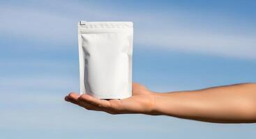 Presentation of a Clean White Resealable Pouch in Hand against a Cloudless Blue Sky, Display of a Blank Mockup Food or Cosmetic Pouch with a Clear Sky Background photo