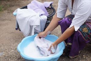 Washing clothes in a plastic basin outdoors. Concept, traditional care and patience reflect sustainable living and love through every gentle scrub and soap bubble. photo