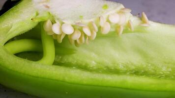 Macro view of tweezers extracting seeds from a sliced green bell pepper under bright lighting video