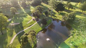 Drone captures a lush golf course with water features and pathways under soft morning light video