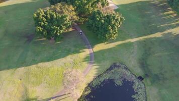 Drone footage captures lush green fairways, trees, and water hazards on a Gold Coast golf course during golden sunset hour video