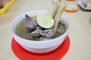 A bowl of soup with meat and vegetables on a table photo