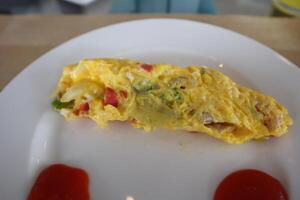 A white plate topped with an omelet and ketchup photo