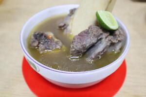 A bowl of soup with meat and lime photo