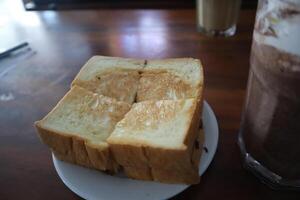 A piece of toast on a plate next to a drink photo