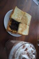 A sandwich on a plate next to a drink photo