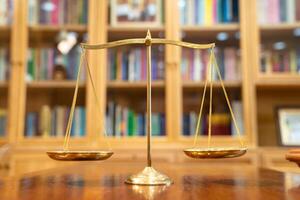 Close up to Golden vintage Scale Symbolic of Legal and Law section is standing on wood base in front of Library shelf. a photo